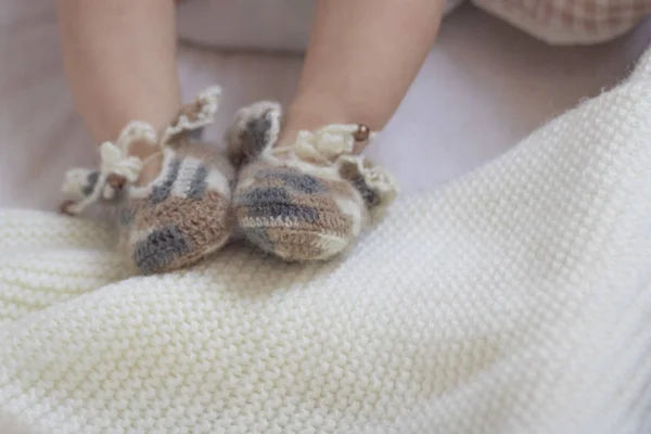 Nouveau-né pieds de bébé fermer en laine marron chaussettes tricotées chaussons sur une couverture blanche. Le bébé est dans le berceau. copyspace — Photo