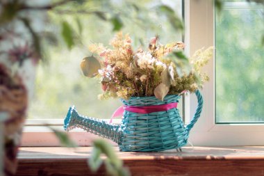 Dekoratif vazo - kuru kır çiçekleri herbaryum ile pembe bir yay ile mavi hasır sulama olabilir, köyde bir kır evinin pencere üzerinde duruyor. Tasarım iç, rustik tarzı. kırsal yaşam
