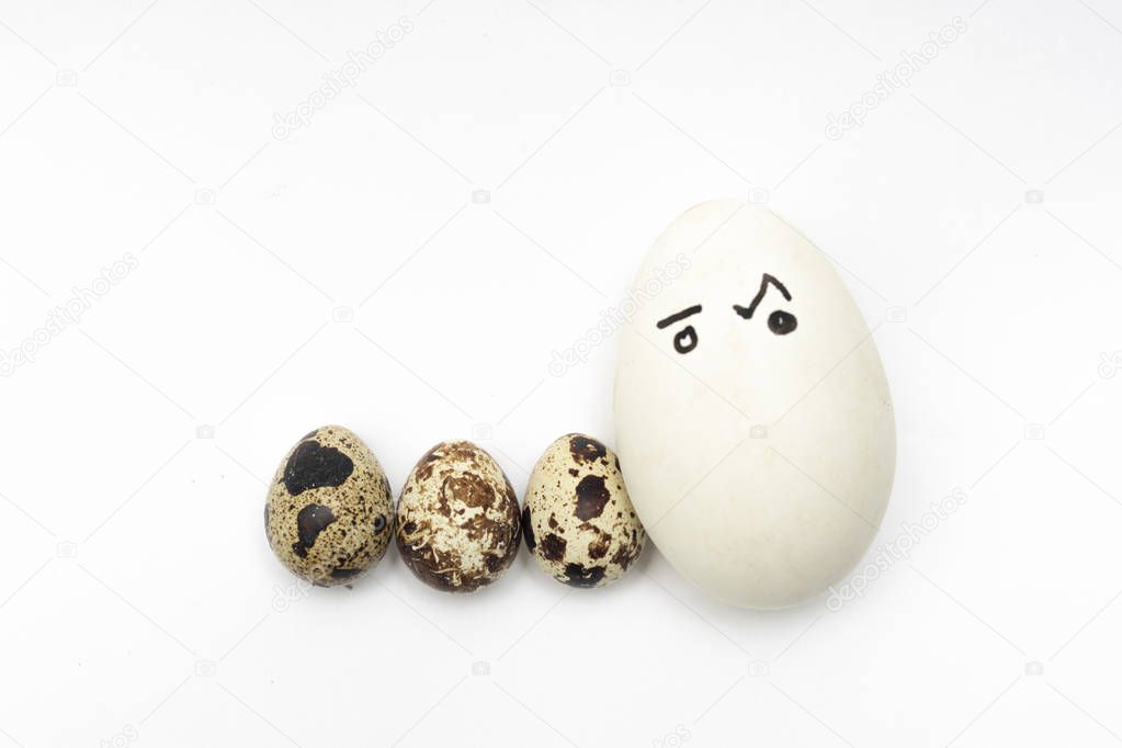 Chicken and quail eggs on a white background symbolize a family with children. Interracial marriage concept, mulatto. Ludicrous images of human persons on chicken eggs.