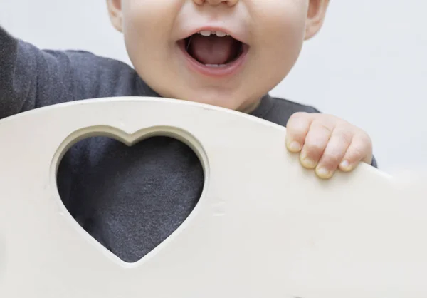 Close-up portrait of a smiling childs mouth. Focus on the heart and place for text, copy space, free space, the child is blurred, out of focus. The concept of health and love, St. Valentine — Stock Photo, Image