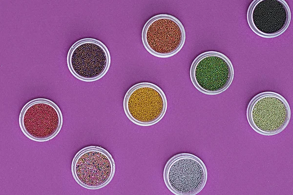 Bottles of Colorful nail glitters, color changing shining powder. Manicure decoration glitter pigment set. Flat lay. Top view sequins for nails and makeup. Sparkles in jar. Pink background