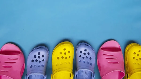 Zapatillas de color brillante para mujeres y niños chanclas sobre un fondo azul. Lugar para el texto — Foto de Stock