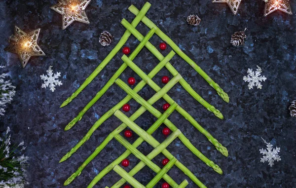 圣诞美食背景。圣诞树上的新鲜芦笋制成的黑色石板背景。健康假日食品, 素食主义, 素食主义和饮食观念 — 图库照片