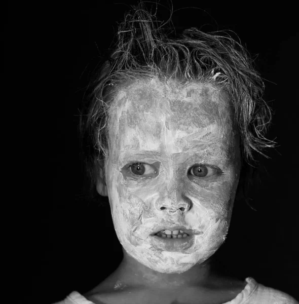 Niño asustadizo con una arcilla blanca untada o cara de maquillaje blanco y negro monocromo —  Fotos de Stock