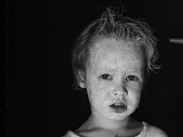 Strašidelné malé dítě s rozmazanou bílou hlínou nebo make-up tvář černobílý — Stock fotografie