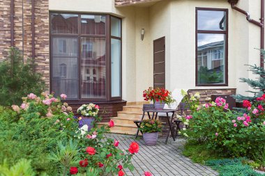 Kasaba evinin girişinde vazolarda çiçekler var. Çiçeklerle süslenmiş merdivenlerle dolu giriş kapısı. Avrupa İtalyan stili