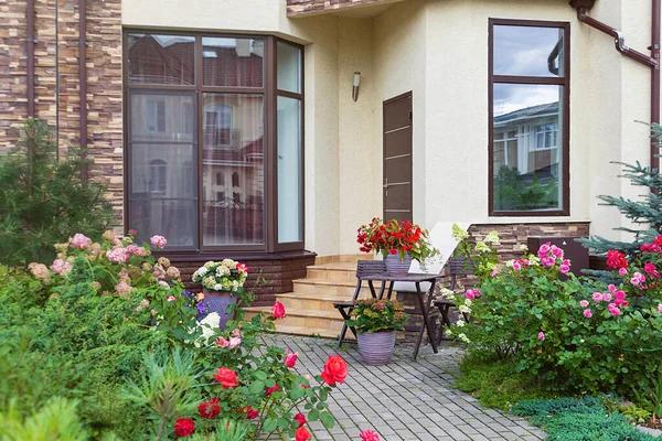 Kasaba evinin girişinde vazolarda çiçekler var. Çiçeklerle süslenmiş merdivenlerle dolu giriş kapısı. Avrupa İtalyan stili