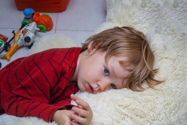 Mutsuz çocuk evde ya da anaokulunda oyuncakların arasında yatıyor ve üzgün ya da uyuyor. Sosyal konsept çocukluk yalnızlığı, hastalık ve üzüntü. Anaokuluna uyum