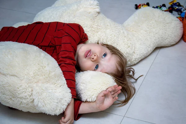 Niño infeliz se acuesta en el suelo en casa o en el jardín de infantes entre los juguetes y está triste o se duerme. Concepto social de soledad, enfermedad y tristeza infantil. Adaptación al jardín de infantes — Foto de Stock