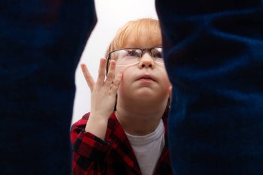 Gözlüklü küçük bir çocuk oturuyor ve korkmuş bir şekilde ayakta duran adama bakıyor. Aile içi şiddet, adam kaçırma ve çocuk istismarı kavramı