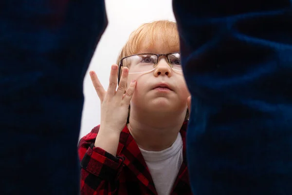 Ein kleiner Junge mit Brille sitzt da und blickt entsetzt zu dem stehenden Mann auf. Häusliche Gewalt, Entführung und Kindesmissbrauch — Stockfoto