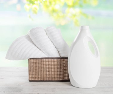 Bascket ve çamaşır jeli beyaz boş şişe beyaz havlu yığını. Renkli arka plana karşı temiz yumuşak havlu yığını.