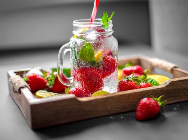 Çilek meyve, nane yaprakları, limon ve limon bir vintage ahşap tepsi üzerinde yarım. Rustik ahşap salver mojito karışımı. Limonata, içecek veya buz, limon, çilek ve nane ile kokteyl. 