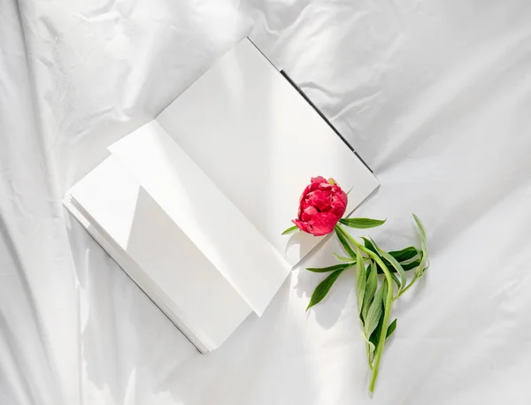 Flores permaneciendo en libro abierto en la cama. Romántico buenos días. Vista superior . — Foto de Stock