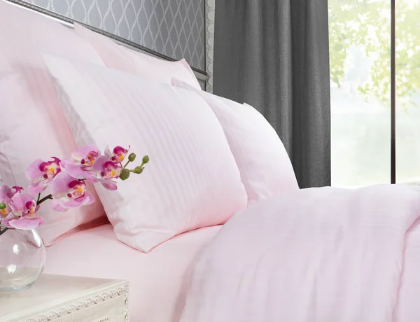 Łóżko z różową pościelą z oknem z szarymi zasłonami. — Zdjęcie stockowe