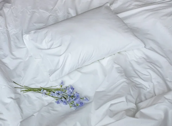 Virágok a rendetlen ágy, fehér ágynemű elemek és kék virágok bouqet — Stock Fotó