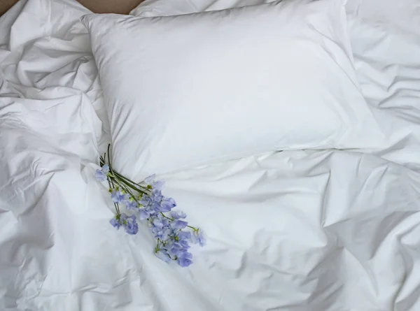 Kwiaty na łóżku bałagan, biały pościel i niebieskie kwiaty bouqet — Zdjęcie stockowe
