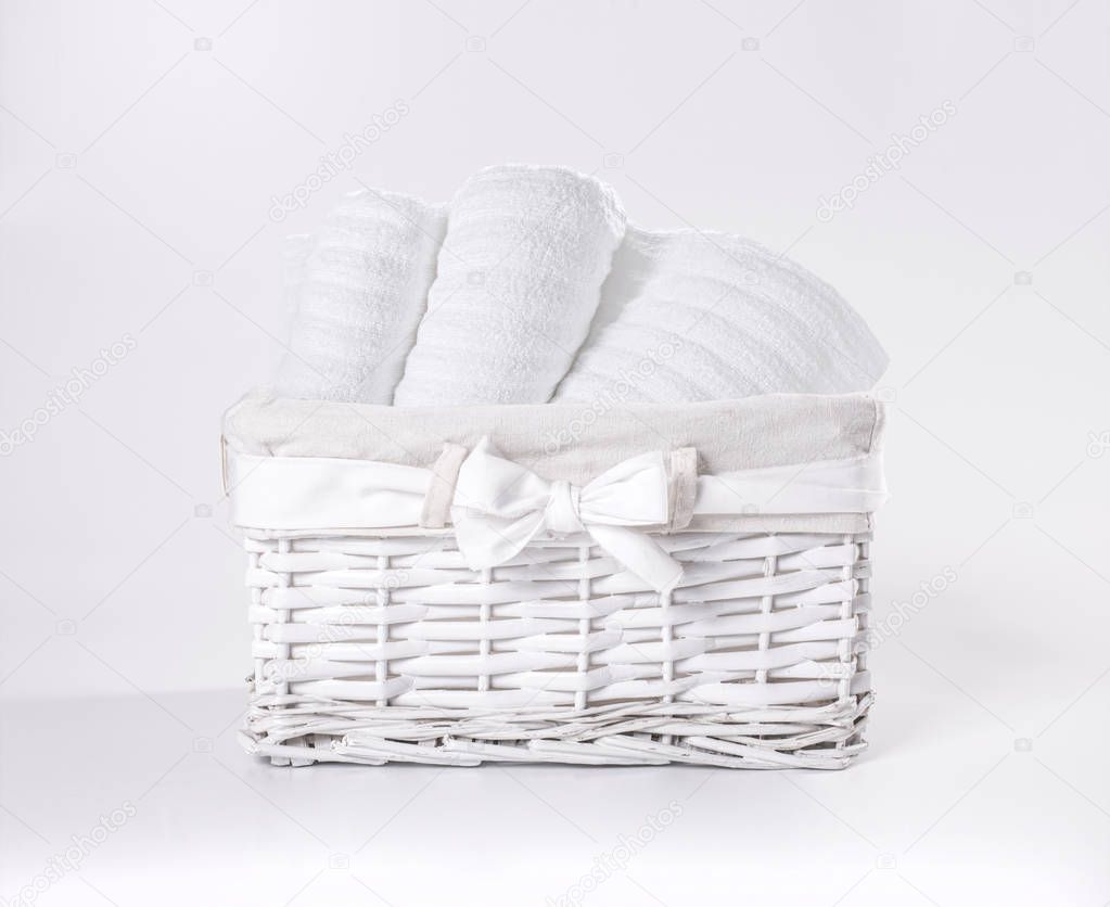 Rolled white soft terry towels in the basket against a white backdrop. Striped towels in a white basket in front of a white backdrop.