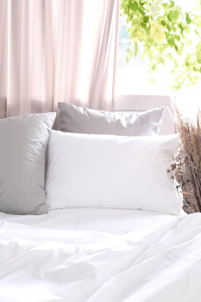 Białe i szare poduszki i koc na łóżku, wnętrze sypialni z oknem, pościel przy oknie — Zdjęcie stockowe