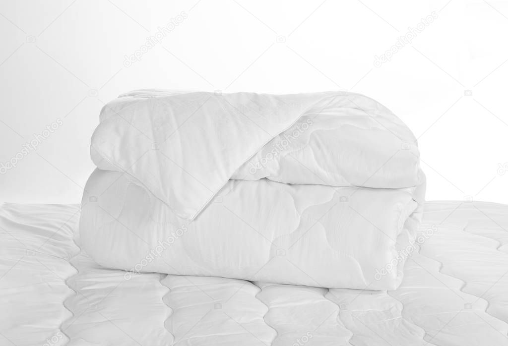 Rolled white soft duvet on the bed against the white background
