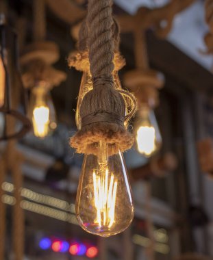 Dükkanın önünde çekilmiş. Halat, kahverengi ip ve sarı ışıkta asılı lambalar