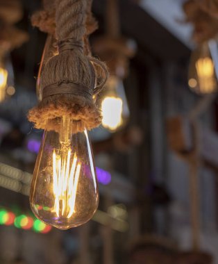 Dükkanın önünde çekilmiş. Halat, kahverengi ip ve sarı ışıkta asılı lambalar