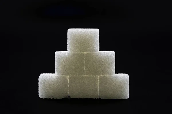 Sugar cubes lined up in pyramid shape. Black background