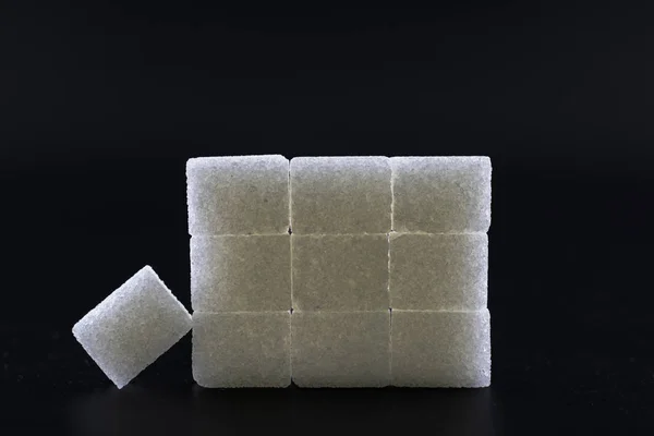 Sugar cubes lined up in pyramid shape. Black background