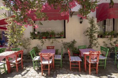 Sokakta Cafe masalar ve sandalyeler ve pembe çiçekler. Sokakta yürüyen insanlar.