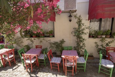 Sokakta Cafe masalar ve sandalyeler ve pembe çiçekler. Sokakta yürüyen insanlar.