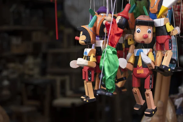 Drewniane zabawki Pinokio stoją na wieszaku. Został zabrany przed sklepem. — Zdjęcie stockowe