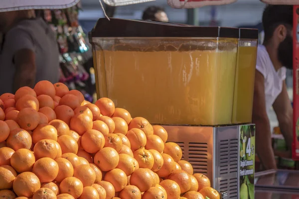 Nahaufnahme der Fruchtsafttheke. Orangen im Vordergrund. Verkäufer und Saftmaschine im Hintergrund — Stockfoto