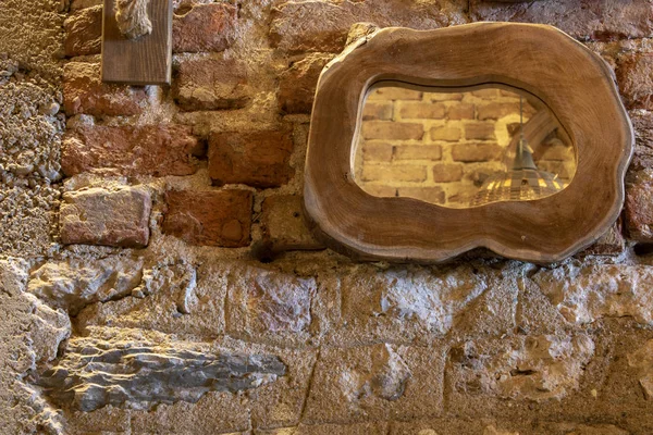 Mirror with wooden frame. Old brick wall in the background.