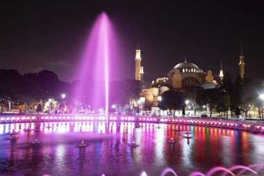 Gece manzaralı ve sokak lambalı Ayasofya Camii. Havuzun kenarından ateş ediyorlar..