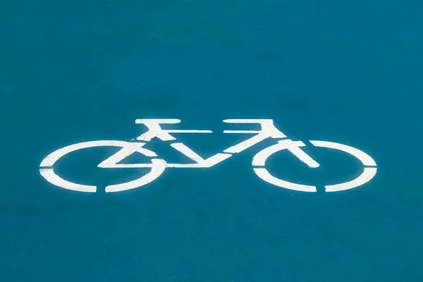 White bike sign on blue bike path background.