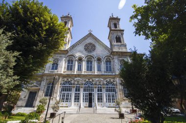 Aya Triada Rom Kilisesi cepheden alınmış. Mavi gökyüzü ve bahçedeki ağaçlar.