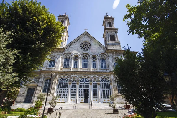 Aya Triada Rom Kilisesi cepheden alınmış. Mavi gökyüzü ve bahçedeki ağaçlar.