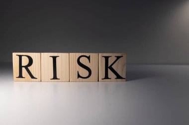 Risk kelimesi tahta küplerle yazıldı. Spot ışıklarının ve beyaz bir masanın üzerinde..