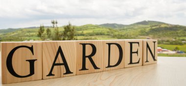 Doğanın arka planında tahta küpten yapılmış GARDEN metni.