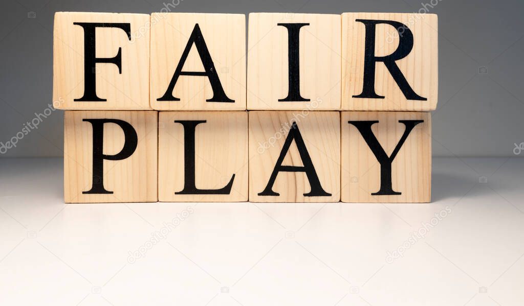 Fair play word from wooden cubes. Spotlight and white background. Sports competitions and law.