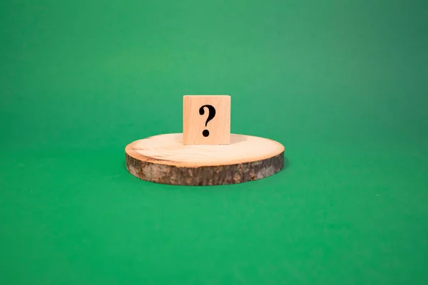 Tahta küplerden yapılmış soru işareti. Arka plan yeşil ve stüdyoda çekilmiş.