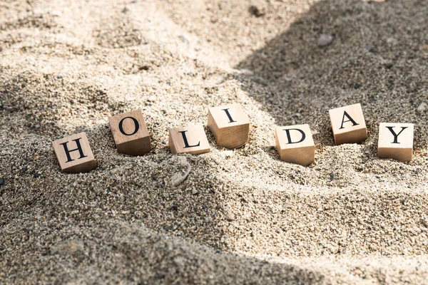 木製のキューブからの休暇の概念 砂や日光の影に埋め込まれた木製のキューブ — ストック写真