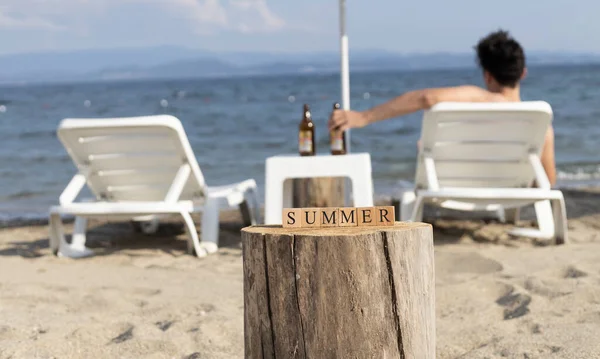 木製のキューブで作られた夏の言葉 ビーチの砂の上でクローズアップ 夏の日に撮影 サングラスと日焼け止めとスリッパがあります — ストック写真