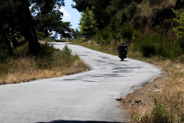 两个村民骑摩托车旅行 他头上没有头盔 森林路上的补丁沥青路面 — 图库照片