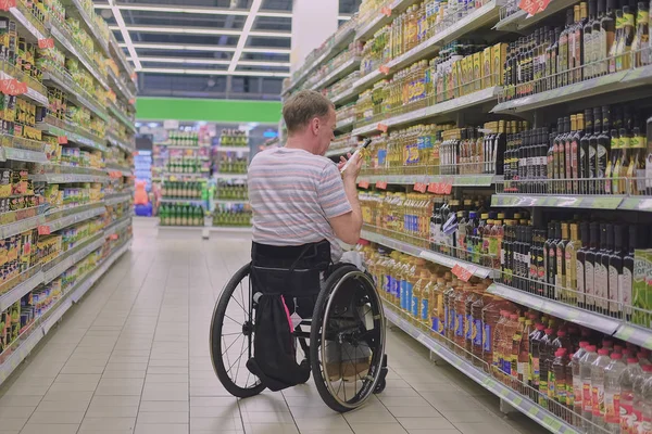 Shopping in sedia a rotelle nel supermercato Immagini Stock Royalty Free