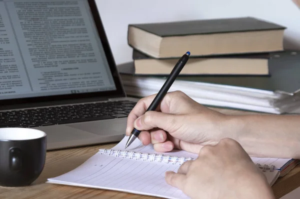 Tomando notas a mano en un cuaderno con hojas negras con los