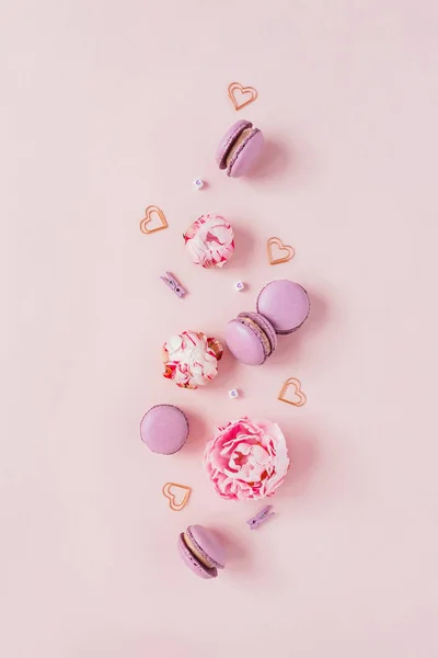 Pembe arka planda macaroons ve çiçekler.