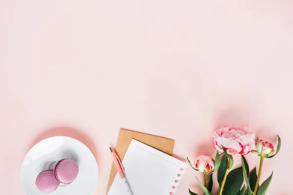 Top view of macaroons with a Cup of tea and peonies. — Stock Photo, Image