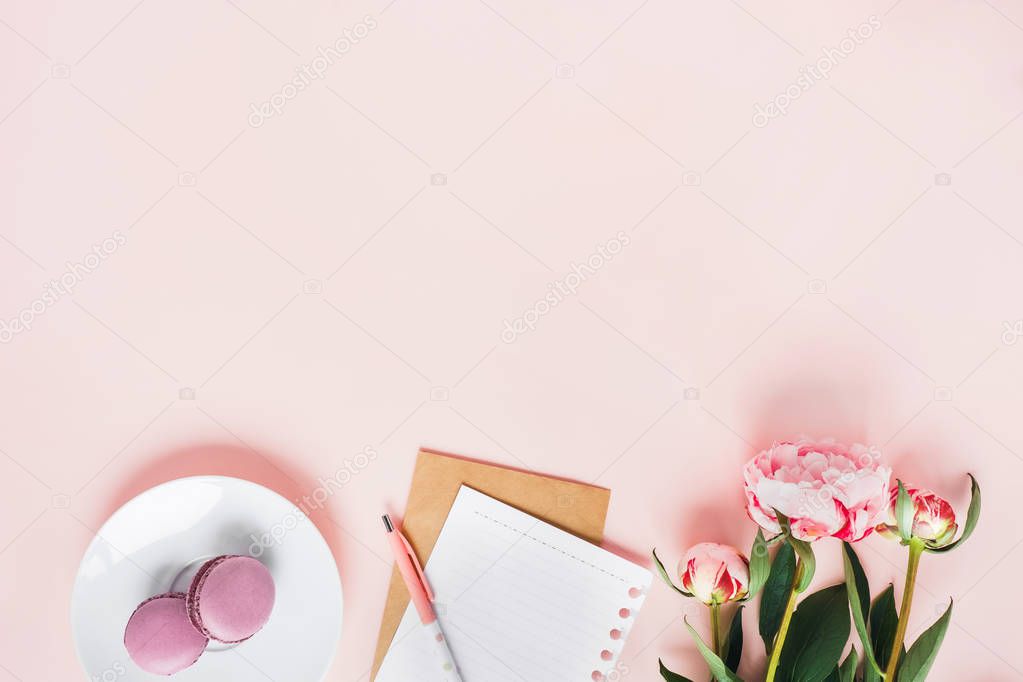 Top view of macaroons with a Cup of tea and peonies.