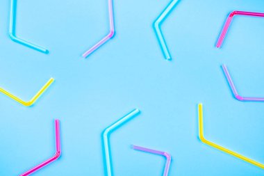 Pembe arka planda renkli kokteyl pipetleri.